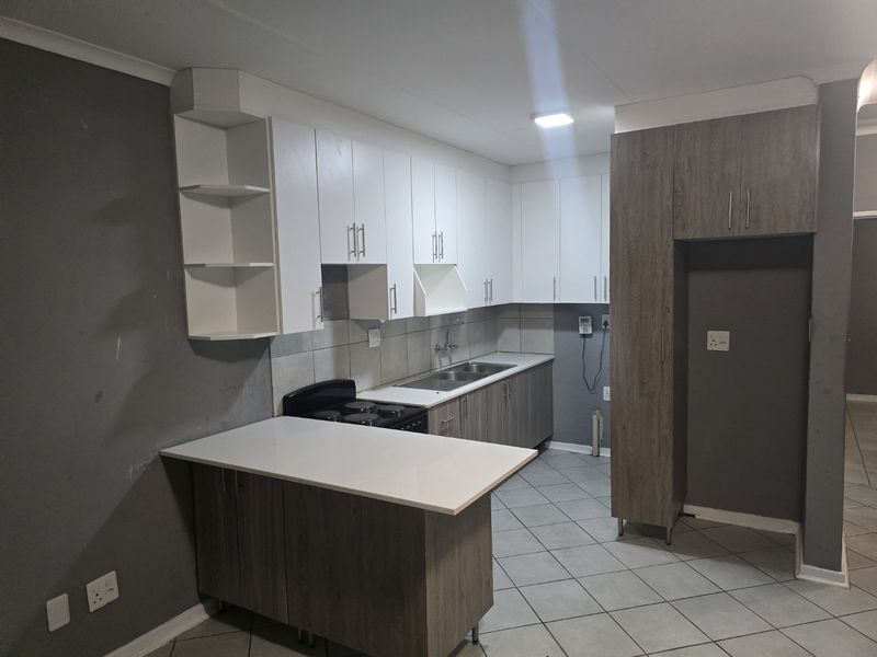A functional kitchen featuring two-tone cabinetry, stone countertops, a double sink, and an electric stove with tiled flooring throughout.