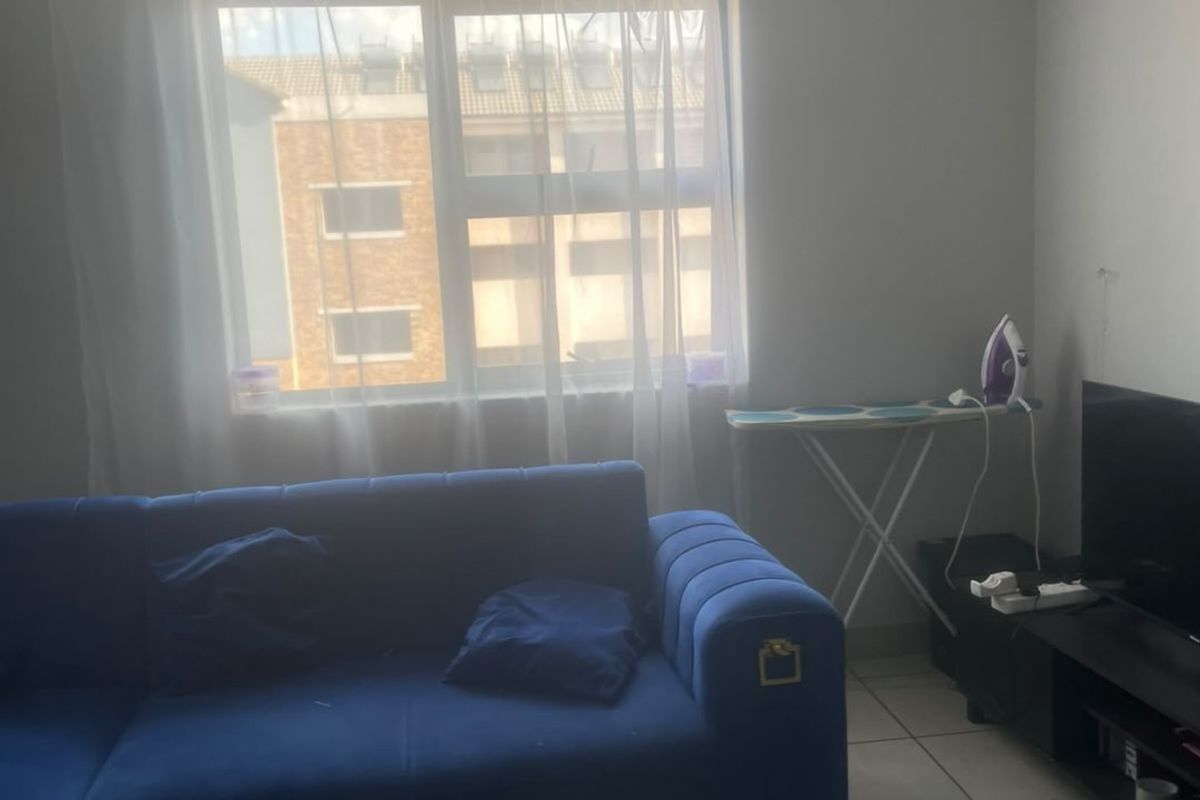 A living room area featuring tiled flooring and a window with natural light.