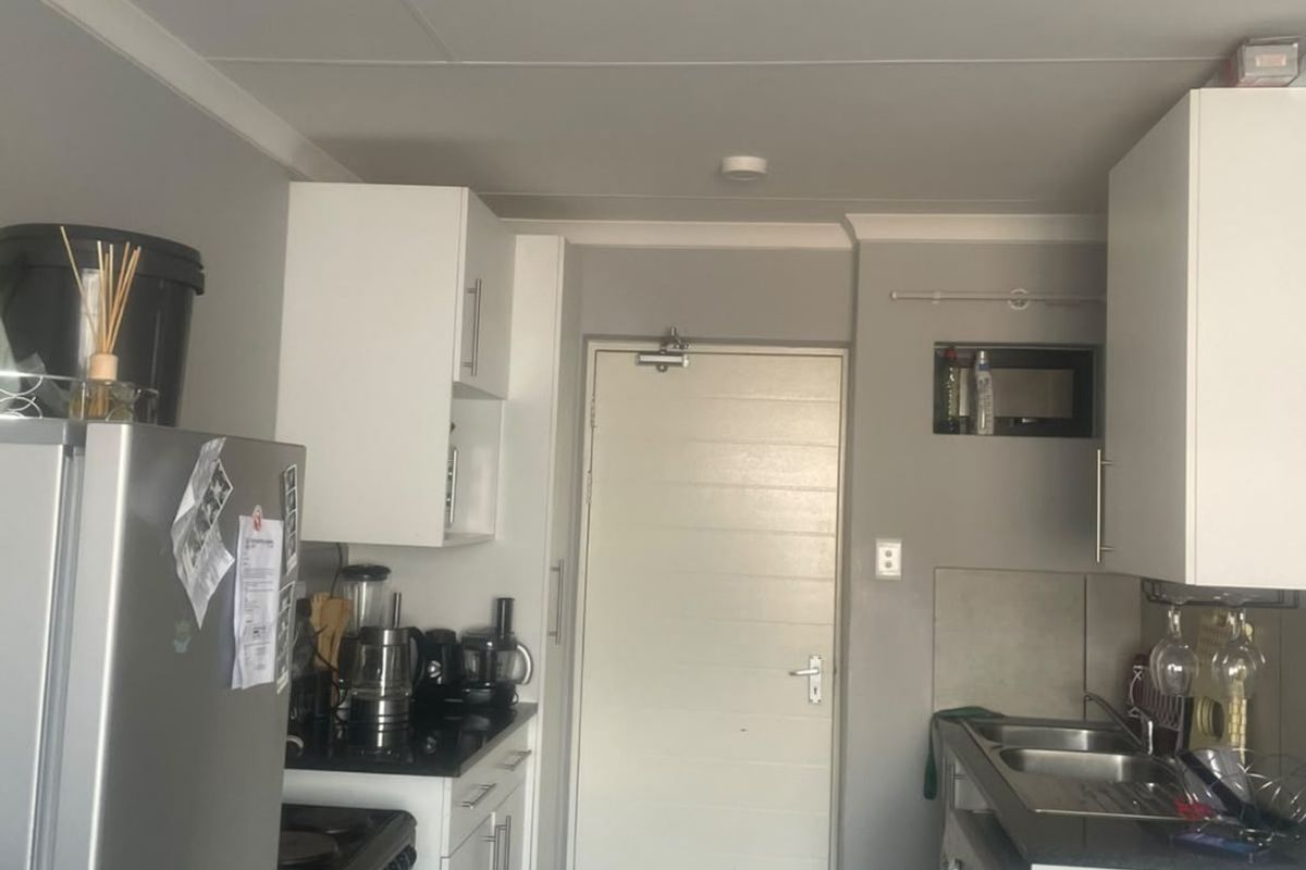 A functional kitchen featuring white cabinetry, dark countertops, a double sink, and tiled flooring, providing a practical layout for daily meal preparation.