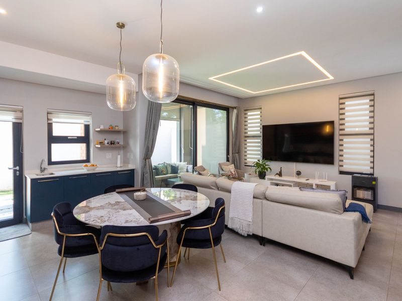 Modern open-plan living and dining area featuring tiled floors, recessed ceiling lighting, and direct access to an outdoor patio through sliding glass doors.