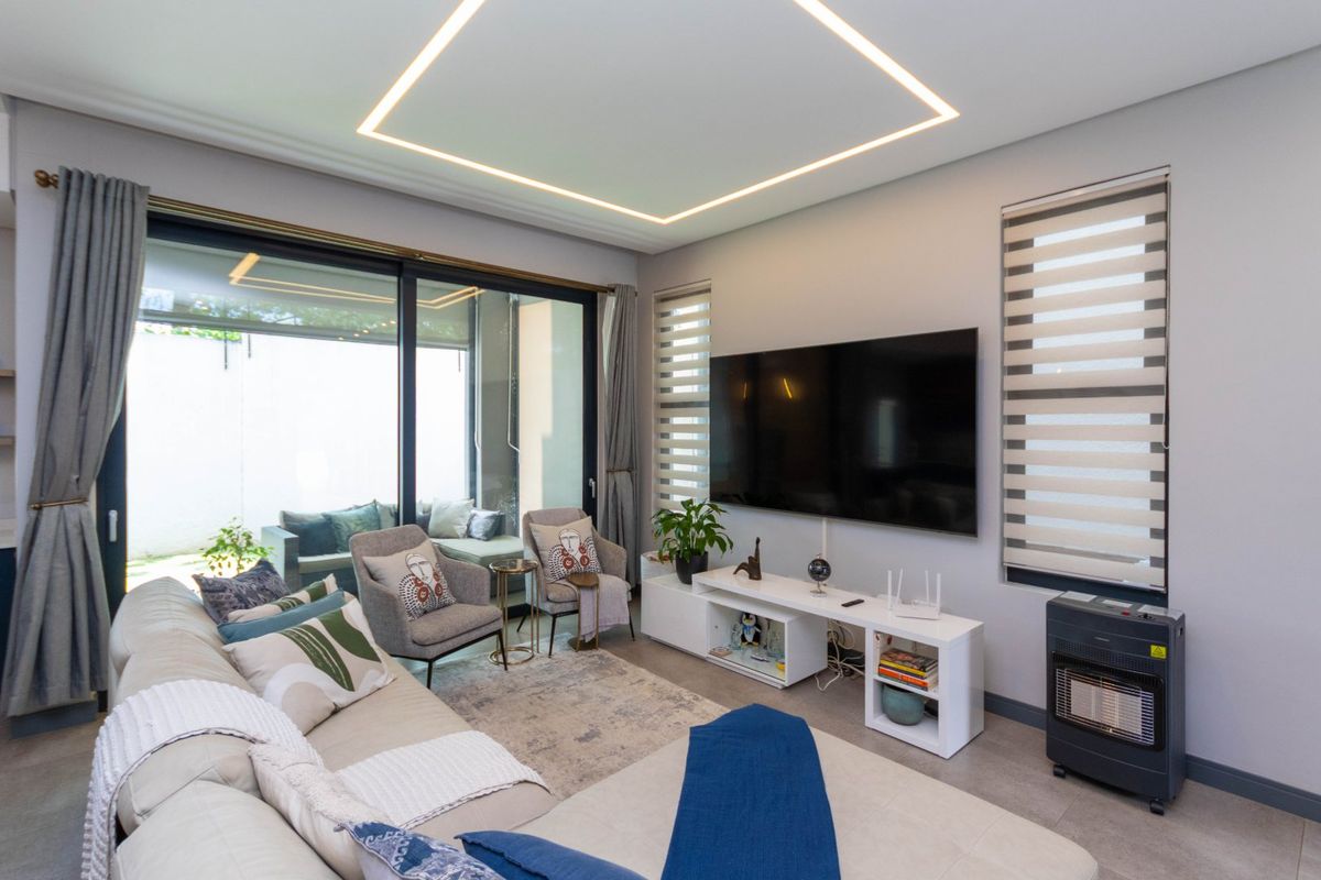 Modern living room featuring recessed ceiling lighting, large sliding glass doors leading to a patio, and neutral tiled flooring.