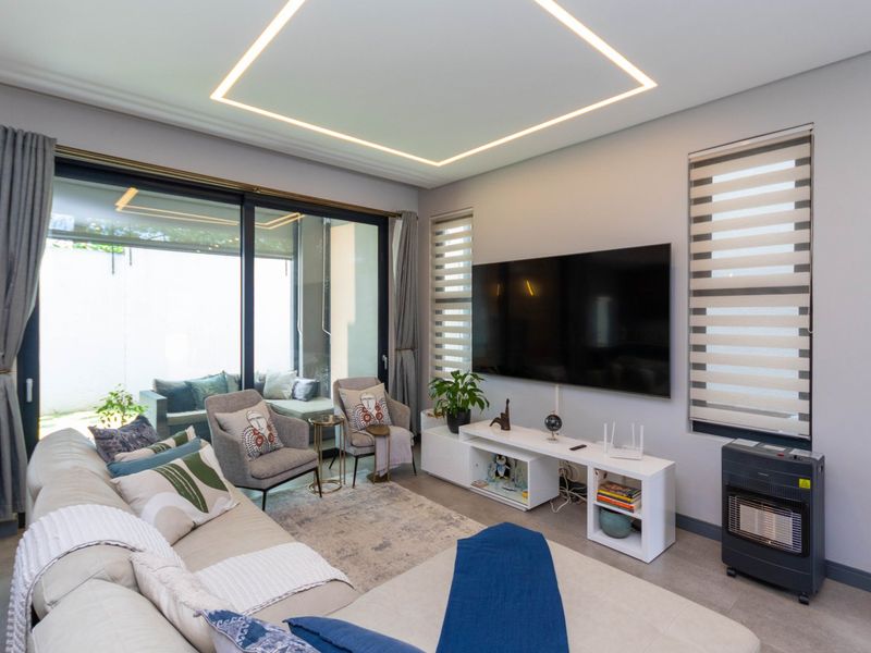 Modern living room featuring recessed ceiling lighting, large sliding glass doors leading to a patio, and neutral tiled flooring.