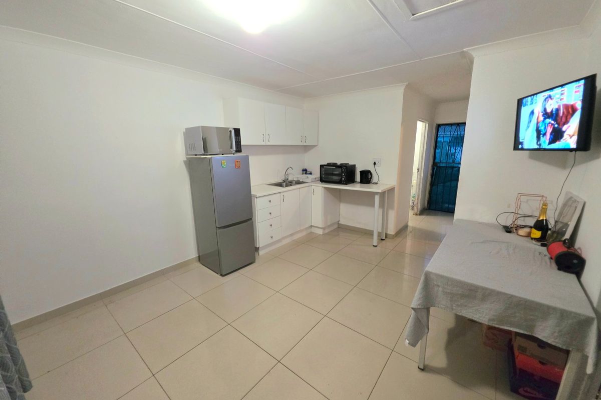 A functional kitchen area featuring white cabinetry, tiled flooring, and a compact workspace, providing a clean and practical layout.