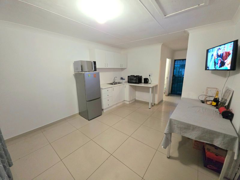 A functional kitchen area featuring white cabinetry, tiled flooring, and a compact workspace, providing a clean and practical layout.