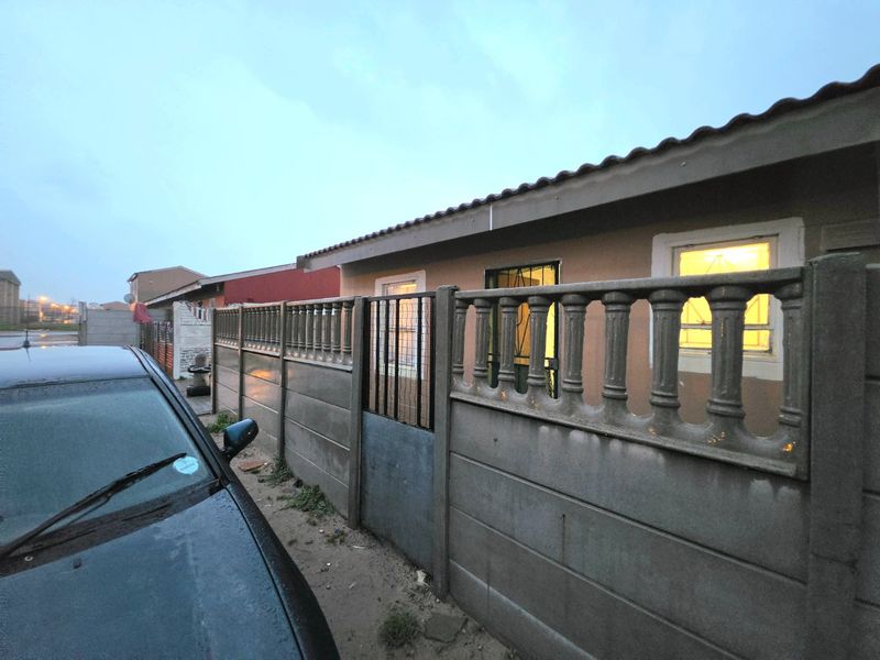 Front exterior view of the property featuring a precast concrete boundary wall with balustrade detailing and a secure metal pedestrian gate.