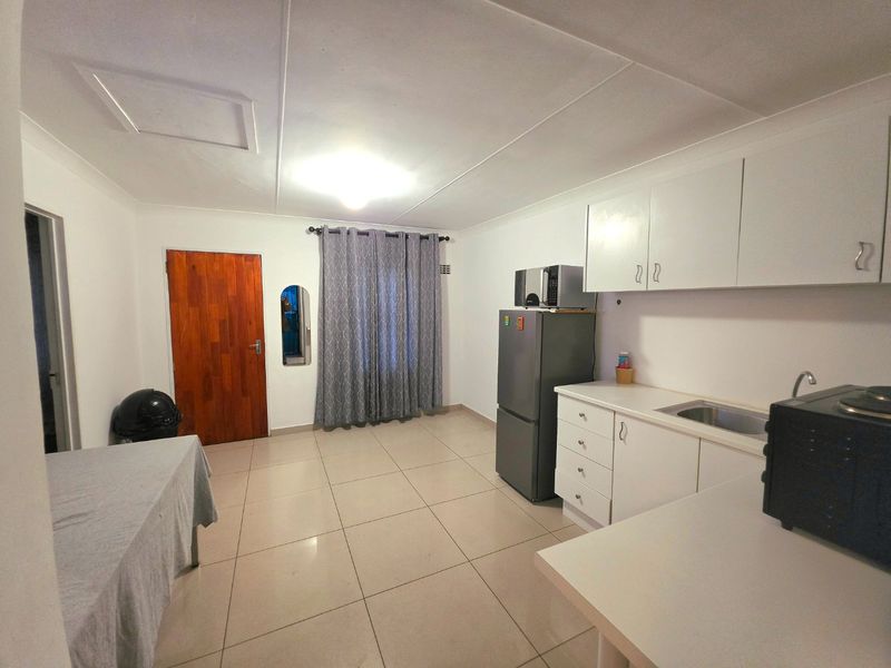 A functional kitchen featuring white built-in cabinetry, tiled flooring, and a stainless steel sink, offering a clean and practical workspace.