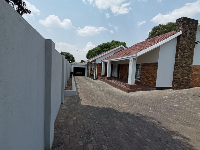 A well-maintained commercial property exterior featuring a paved driveway, brick and plaster facade, tiled roof, and a covered entrance porch.