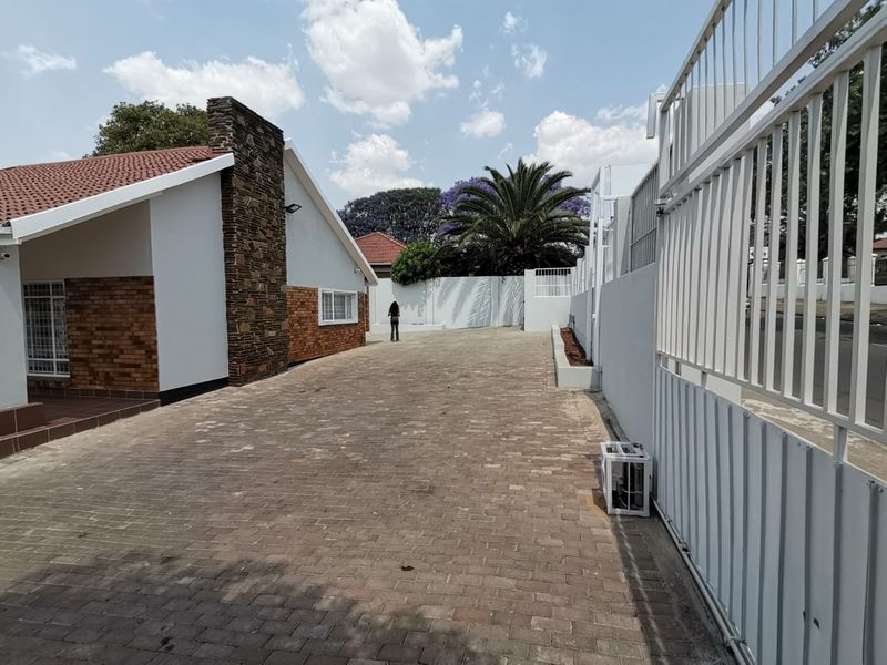 A well-maintained commercial property exterior featuring a paved driveway, secure perimeter walling, and a combination of brick and stone architectural finishes.