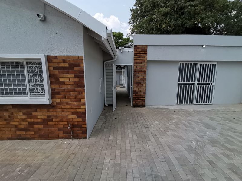 A well-maintained rear courtyard area featuring paved flooring, brick accents, and secure access points with fitted security gates and bars.
