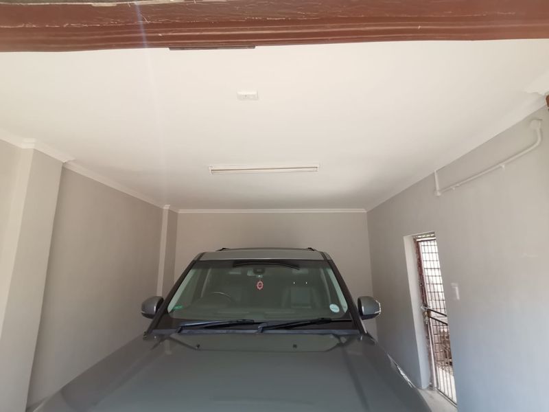 A clean, well-maintained garage space featuring neutral wall finishes, coving, and a secure access door.