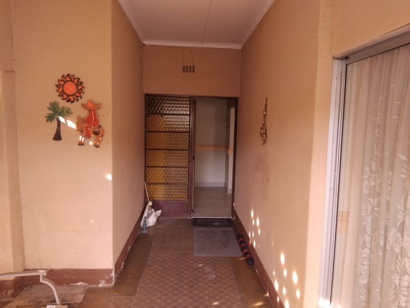 A covered patio area featuring tiled flooring and a sliding door entrance, providing a functional outdoor transition space.