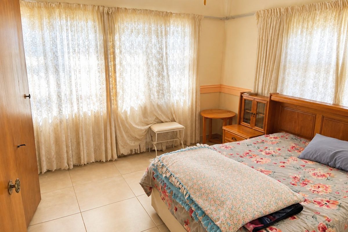 A bedroom featuring tiled flooring, a built-in wardrobe, and a picture rail, offering a functional space with natural light.
