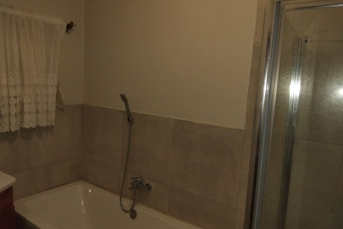 A functional bathroom featuring a bathtub with a handheld shower attachment and a separate shower enclosure with tiled walls.