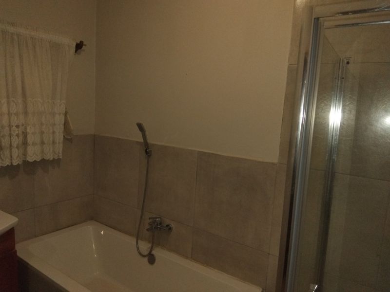 A functional bathroom featuring a bathtub with a handheld shower attachment and a separate shower enclosure with tiled walls.