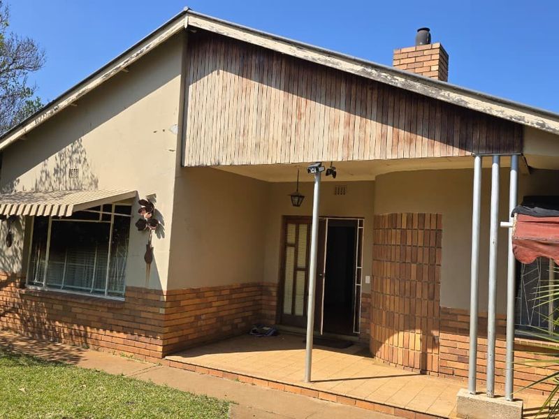 Front elevation of a single-story house featuring a covered porch, brick accents, and timber cladding, set within a garden area.