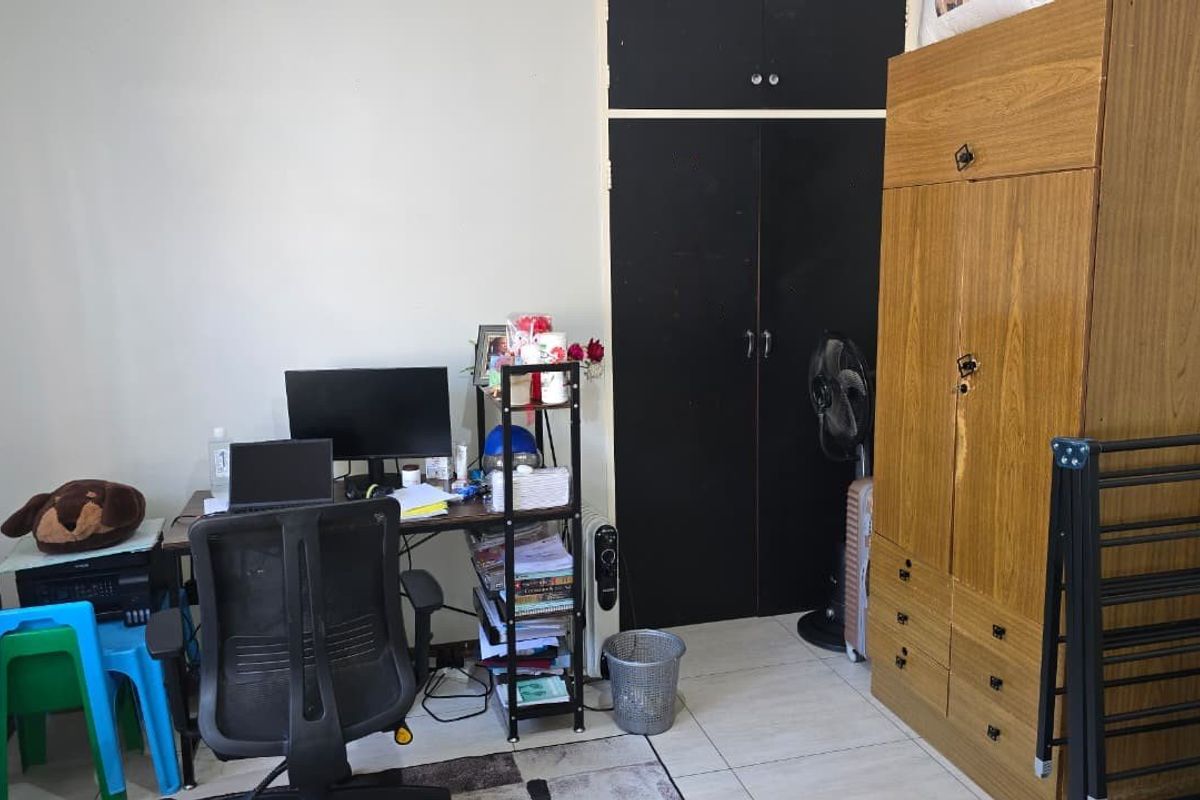 A bedroom featuring a built-in cupboard with black doors and tiled flooring.