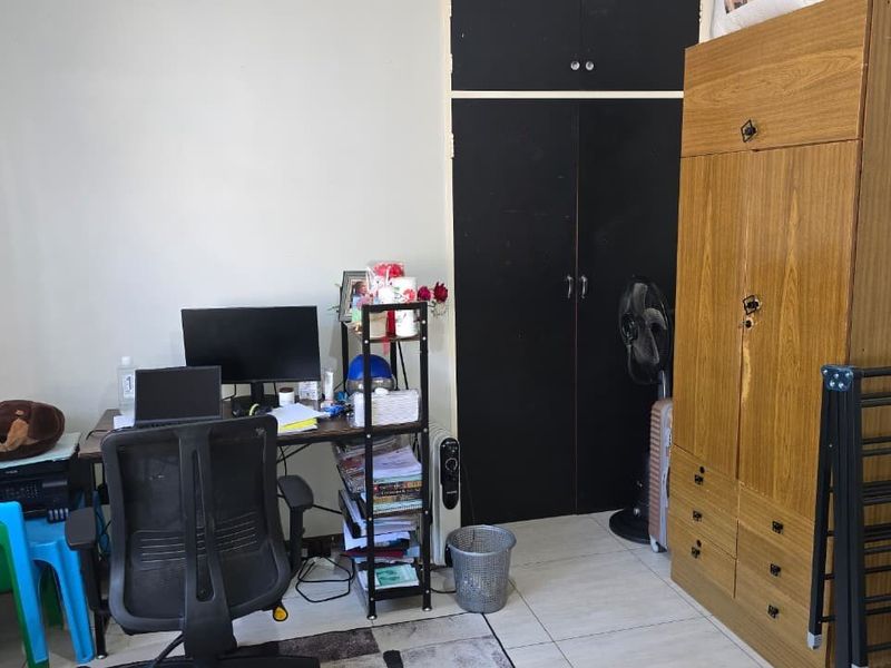 A bedroom featuring a built-in cupboard with black doors and tiled flooring.