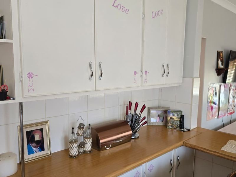 A functional kitchen area featuring white cabinetry, tiled backsplash, and laminate countertops, offering a clean and practical workspace.