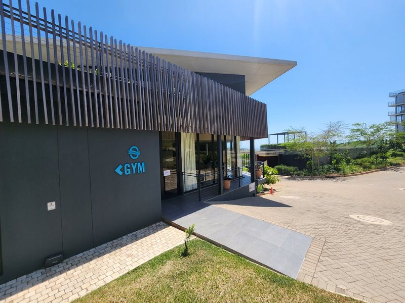 Modern clubhouse exterior featuring a contemporary timber slat facade, paved driveway, and accessible concrete ramp entrance.