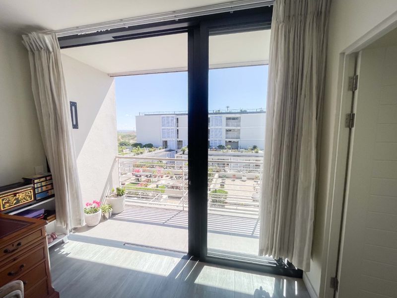 Bedroom featuring large sliding glass doors that open onto a private balcony with views of the apartment complex courtyard.