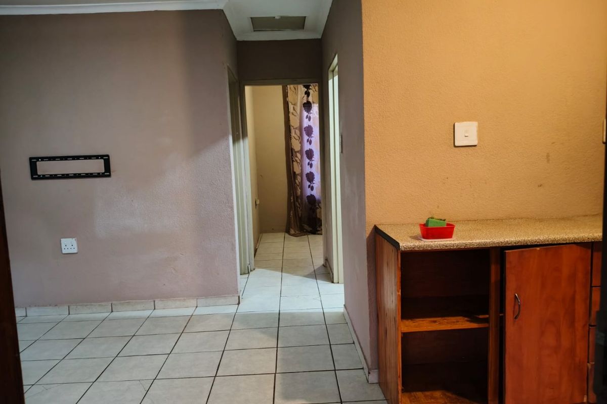 A functional hallway area featuring tiled flooring, built-in cabinetry with a laminate countertop, and access to adjacent rooms.