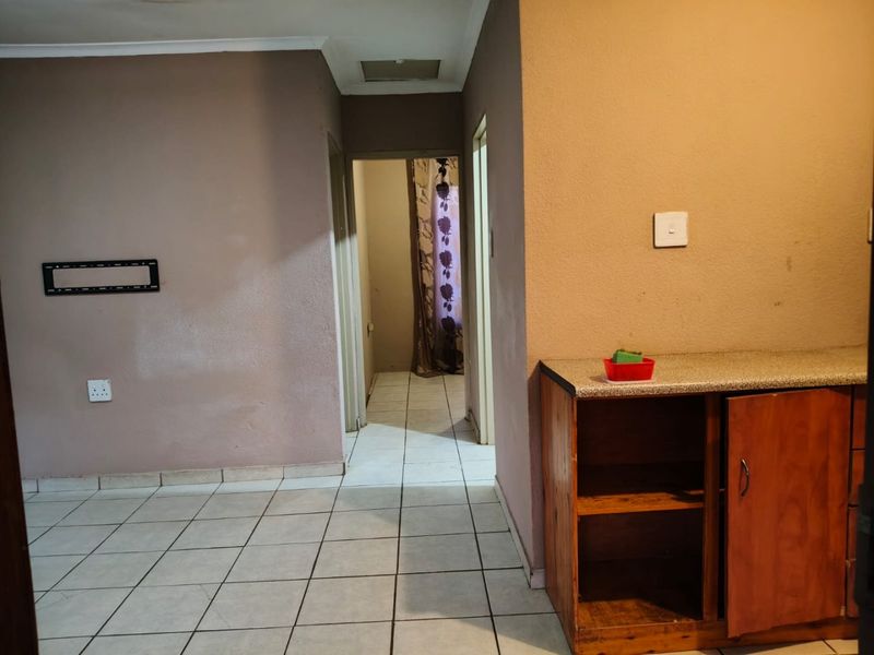A functional hallway area featuring tiled flooring, built-in cabinetry with a laminate countertop, and access to adjacent rooms.