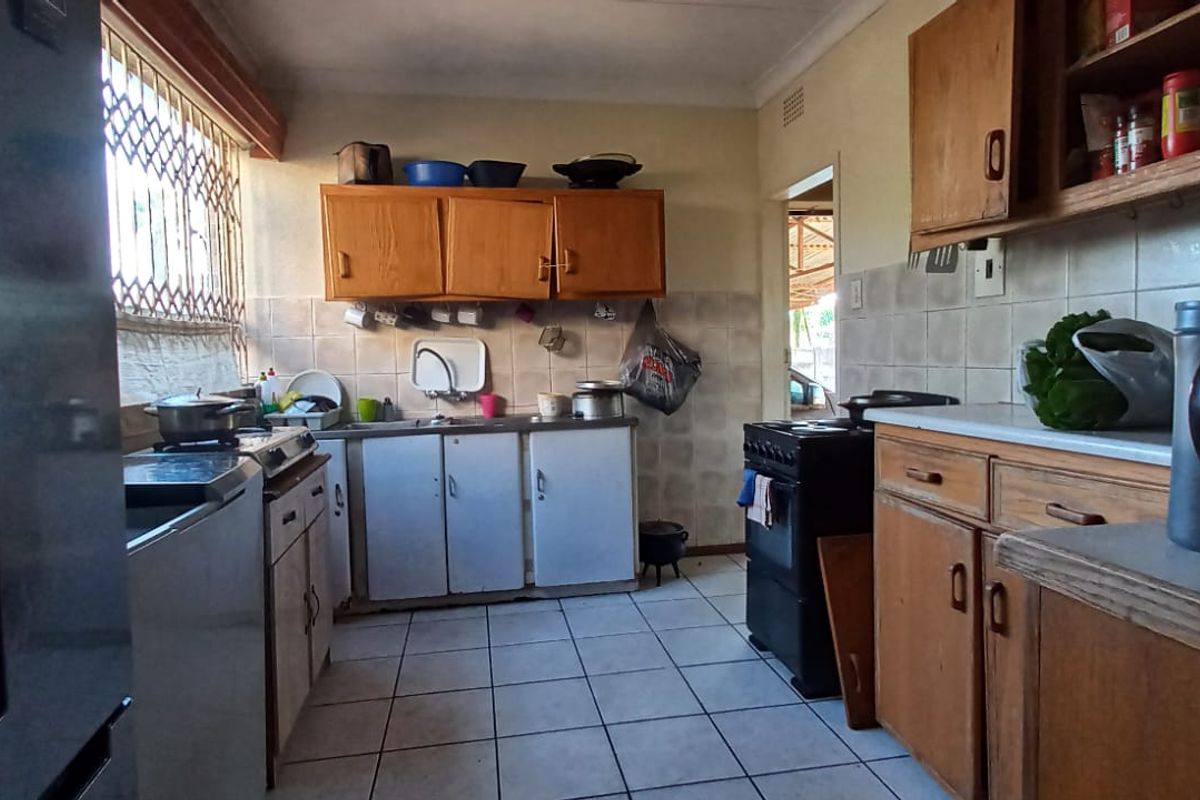 A functional kitchen featuring wooden cabinetry, tiled backsplash, and tiled flooring, offering a dated aesthetic with potential for modernization.