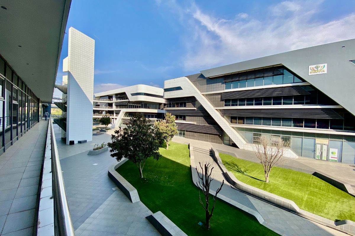 A modern commercial office complex featuring contemporary architectural design, glass facades, metal sun-shading louvers, and a well-maintained landscaped courtyard area.