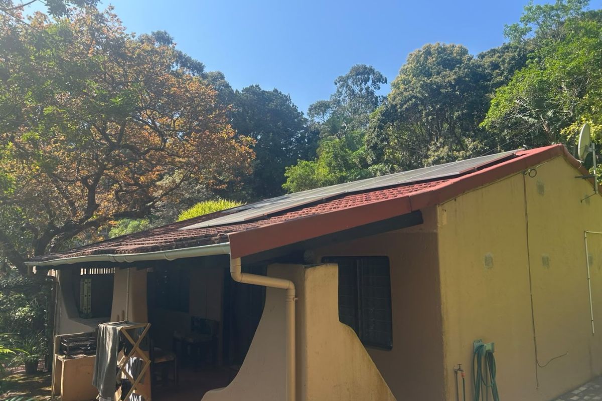 Rear view of the property featuring a tiled roof with installed solar panels, guttering system, and exterior wall finishes.