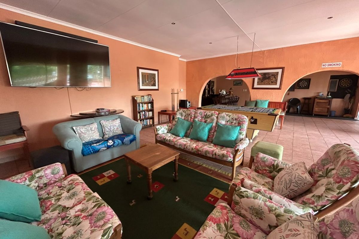Spacious living area featuring tiled flooring and arched architectural details, providing an open-plan flow into the adjacent entertainment space.
