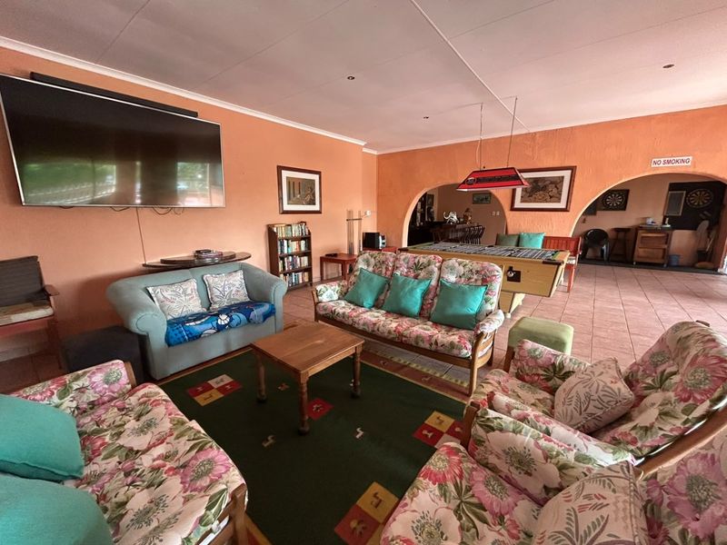 Spacious living area featuring tiled flooring and arched architectural details, providing an open-plan flow into the adjacent entertainment space.