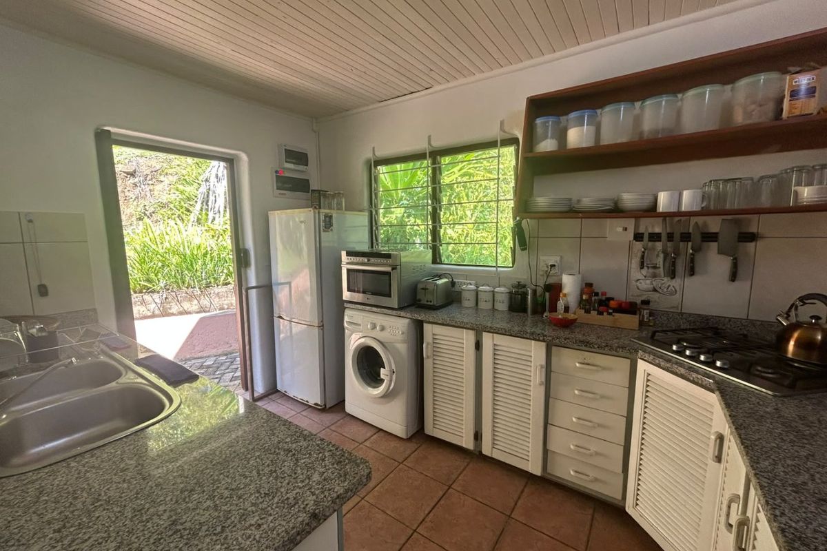 Functional kitchen featuring granite countertops, louvered cabinetry, built-in gas hob, and direct access to the outdoor area.