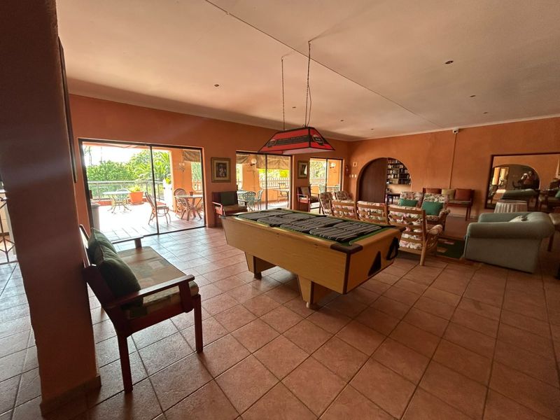 Spacious living area featuring terracotta floor tiles, recessed lighting, and large sliding glass doors providing access to an outdoor patio.