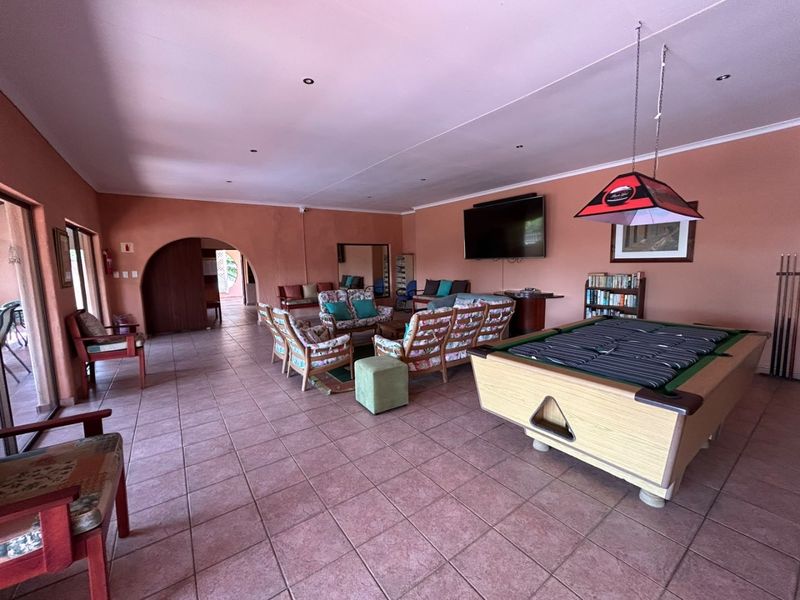 Spacious living area featuring tiled flooring, recessed lighting, and an arched entryway, providing a versatile space for relaxation and entertainment.