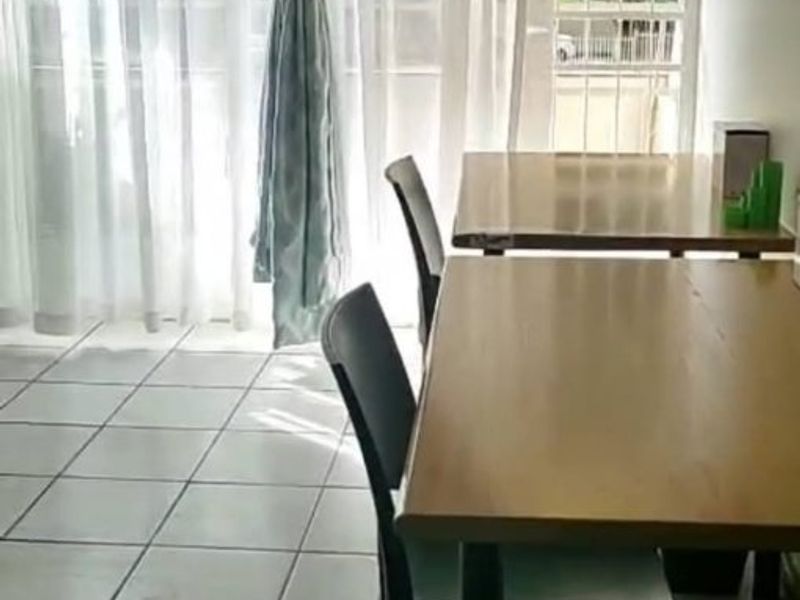 A living area featuring tiled flooring and a sliding door leading to an outdoor space with a security gate.