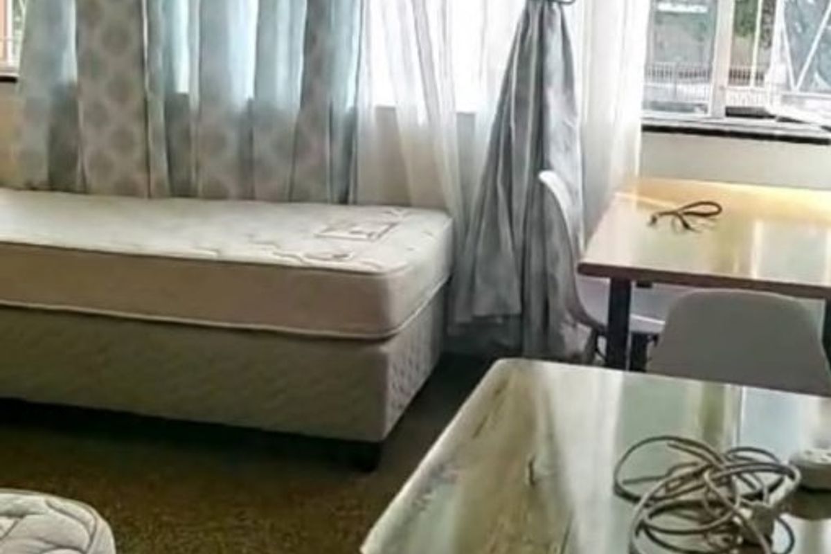 A bedroom featuring large windows with curtains and carpeted flooring, offering potential for modernization and improved interior finishes.