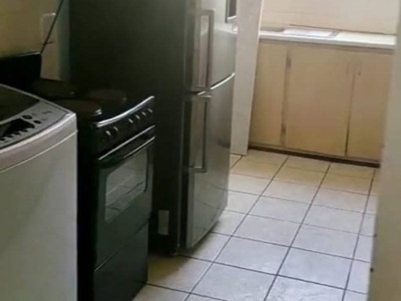 A functional kitchen space featuring tiled flooring, built-in cabinetry, and a sink, currently showing signs of age and wear.
