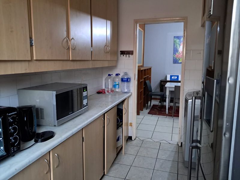 A functional kitchen featuring laminate cabinetry, tiled backsplash, and tiled flooring, showing signs of wear and requiring cosmetic updates.
