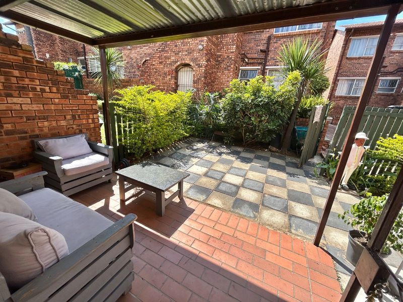 A covered outdoor patio area featuring brick walls, paved flooring, and a corrugated metal roof, providing a functional space for outdoor relaxation.