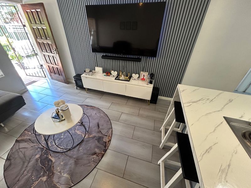 Open-plan living area featuring modern slatted wall paneling, tiled flooring, and a marble-look breakfast bar, creating a contemporary and functional space.