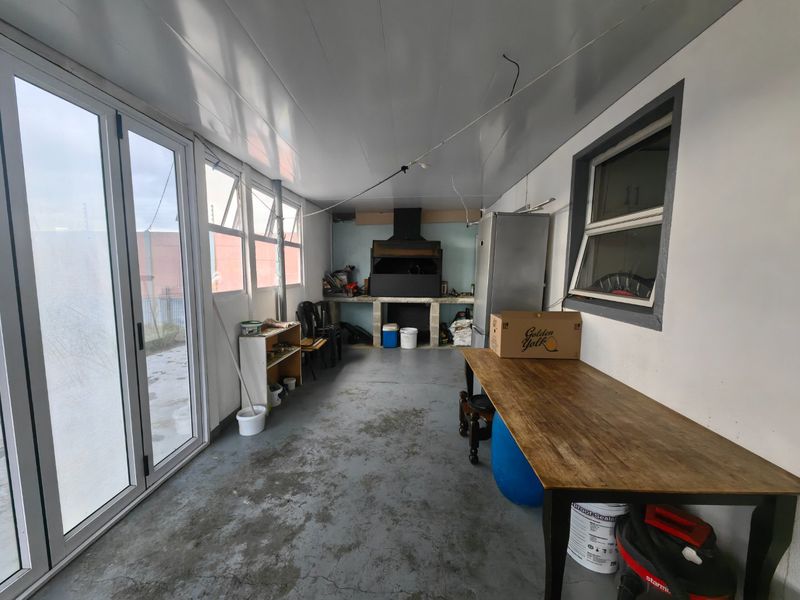 Enclosed patio area featuring a built-in braai, extractor fan, and sliding glass doors, offering a versatile space for outdoor entertaining.