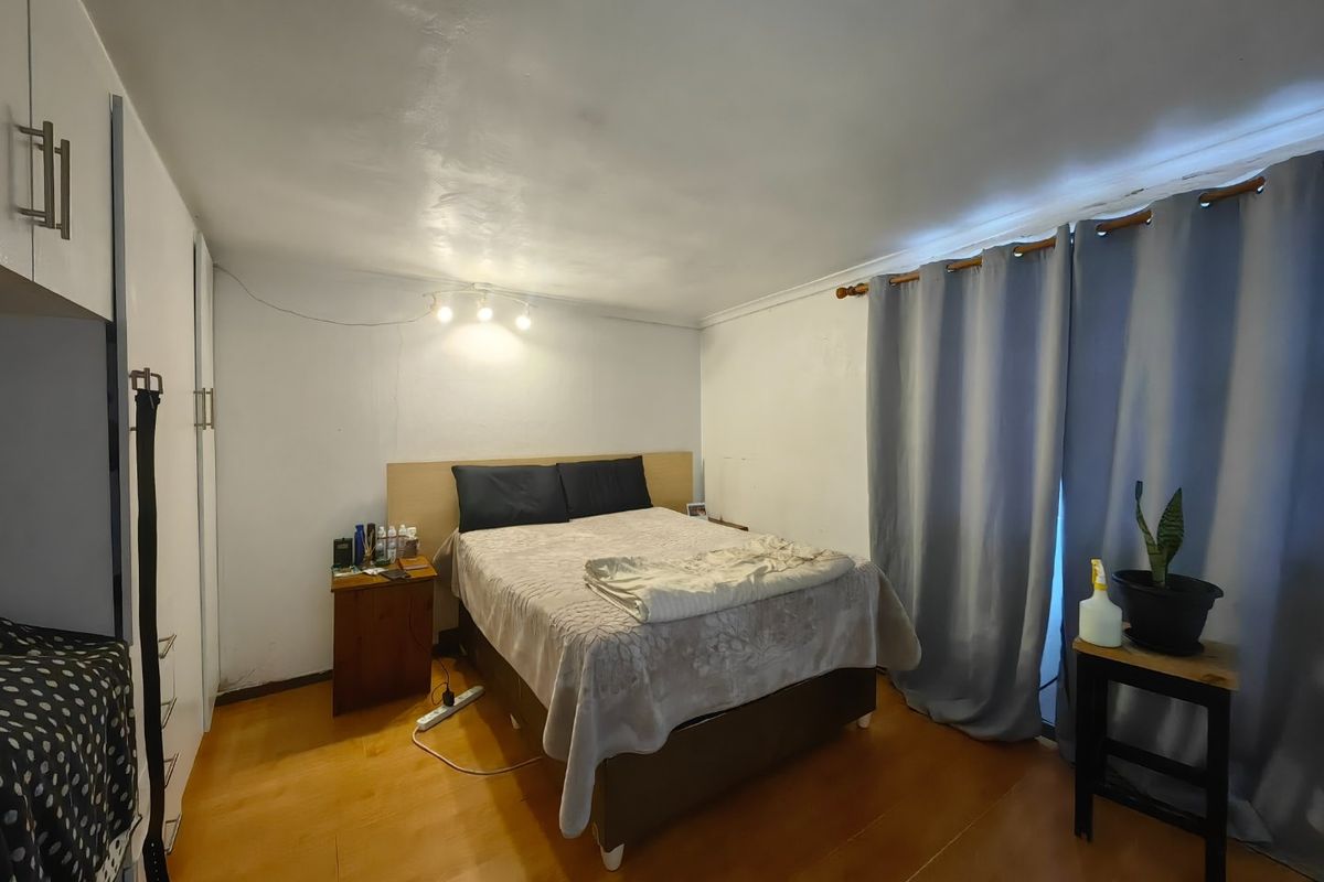 A bedroom featuring laminate flooring, built-in cupboards, and direct access to a patio area via sliding doors.