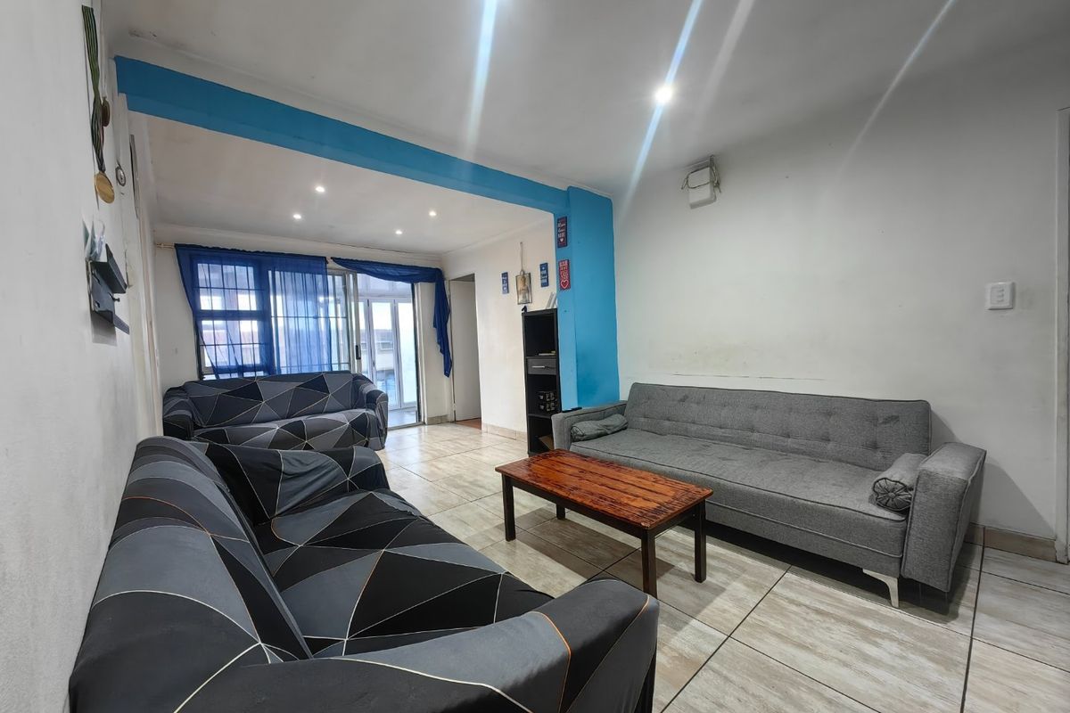 A living room featuring tiled flooring, recessed downlighting, and a sliding glass door providing access to the exterior.