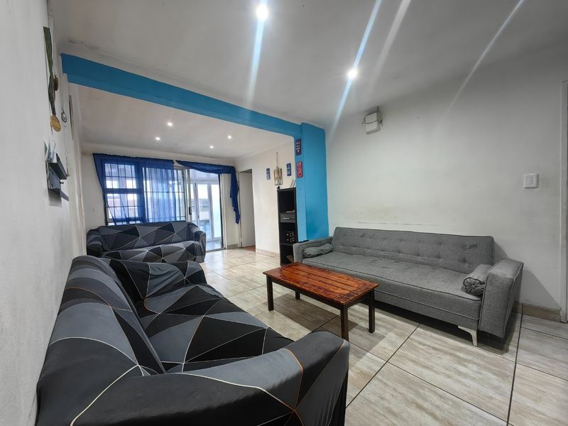 A living room featuring tiled flooring, recessed downlighting, and a sliding glass door providing access to the exterior.