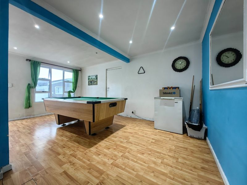 A multi-purpose living area featuring laminate flooring, recessed downlighting, and blue accent walls, currently utilized as a recreational space.
