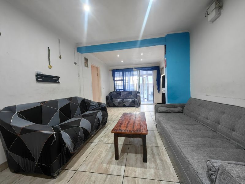 A spacious living area featuring tiled flooring, recessed lighting, and a sliding glass door providing access to the exterior.