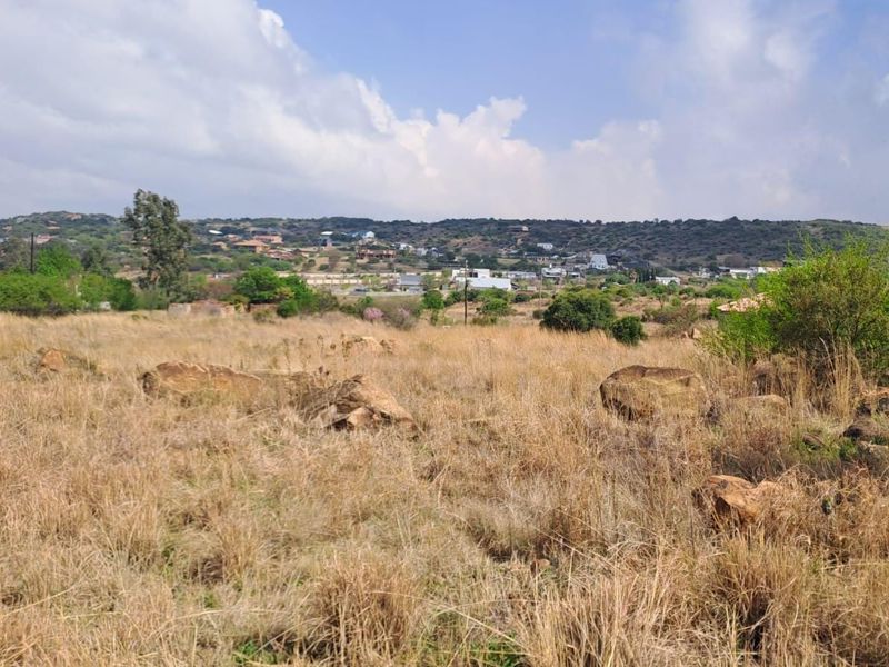 A scenic view of the surrounding landscape and distant residential area, featuring natural vegetation and rocky terrain.
