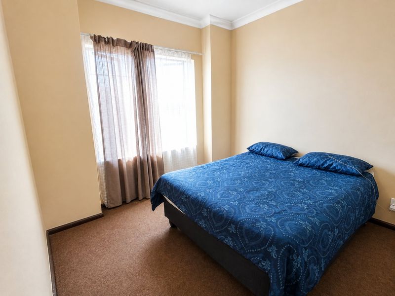 A simple bedroom featuring neutral wall paint, carpet flooring, and a window with installed curtain rods.