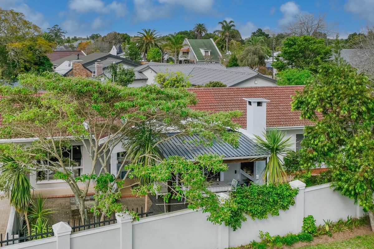 Aerial view of the rear exterior featuring a tiled roof, covered patio with a built-in fireplace, and a secure boundary wall.