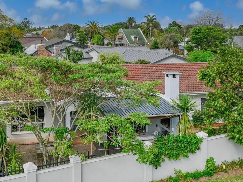 Aerial view of the rear exterior featuring a tiled roof, covered patio with a built-in fireplace, and a secure boundary wall.